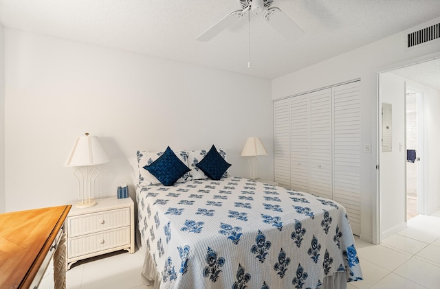 bedroom with a textured ceiling, a closet, ceiling fan, and light tile patterned flooring