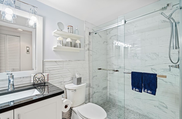 bathroom featuring walk in shower, vanity, toilet, and tile walls