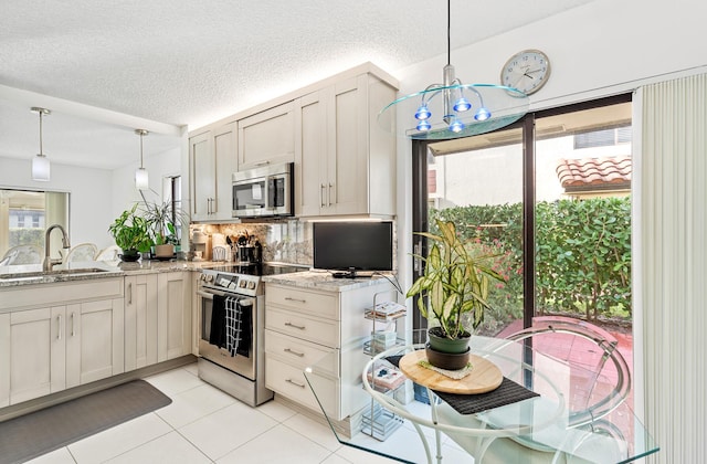 kitchen with appliances with stainless steel finishes, pendant lighting, sink, backsplash, and light stone countertops