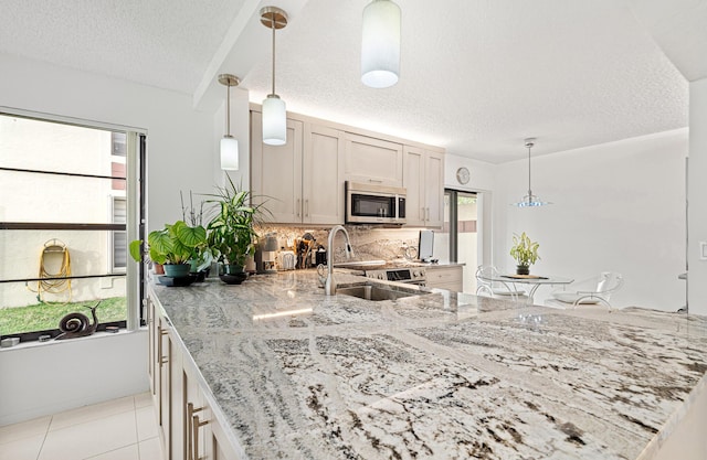 kitchen featuring stainless steel appliances, light stone countertops, a textured ceiling, light tile patterned flooring, and decorative backsplash