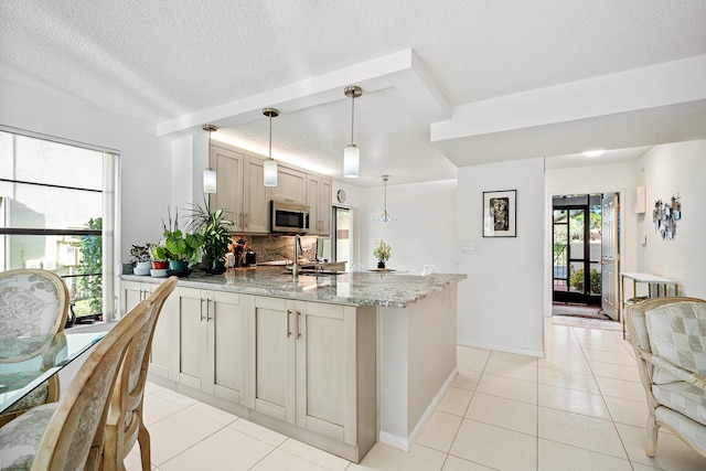 kitchen featuring light tile patterned floors, sink, light stone counters, a kitchen island, and decorative light fixtures