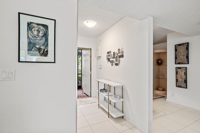 hallway featuring a textured ceiling and light tile patterned flooring