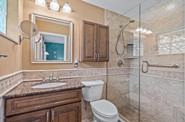 bathroom with vanity, toilet, an enclosed shower, and tile walls