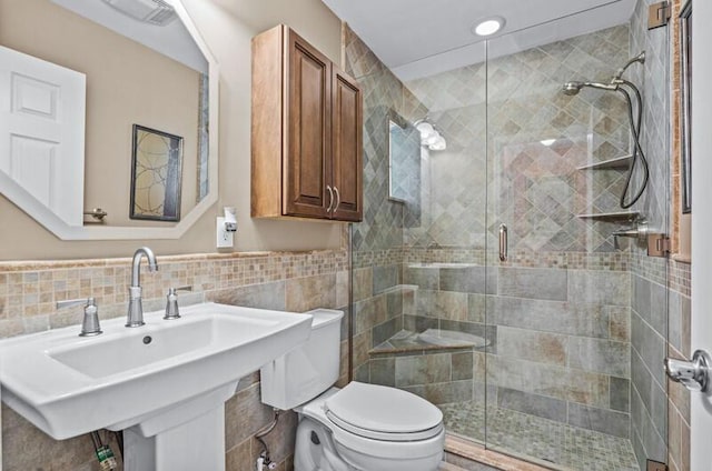 bathroom with sink, a shower with shower door, and toilet