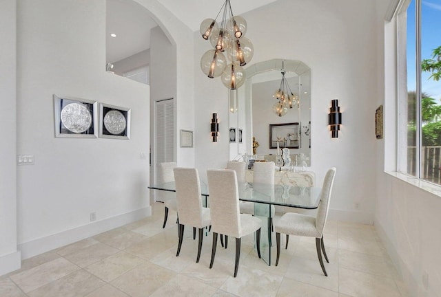 tiled dining space with a towering ceiling and a chandelier