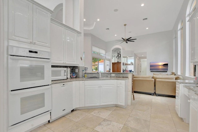 kitchen featuring sink, white cabinetry, light stone counters, white appliances, and backsplash