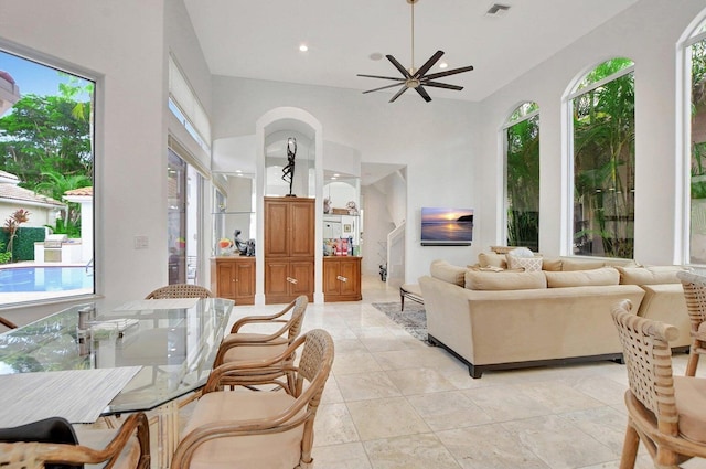 tiled living room featuring a towering ceiling, plenty of natural light, and ceiling fan