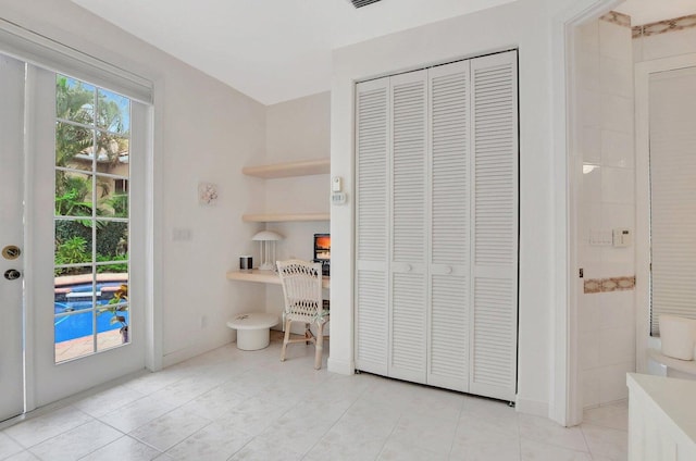 interior space with multiple windows, access to outside, built in desk, and a closet