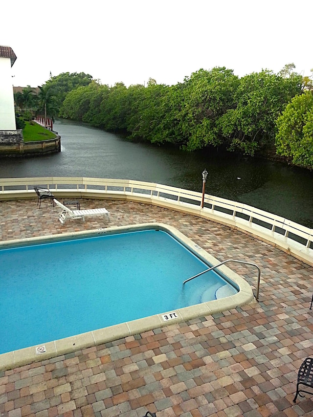 view of swimming pool featuring a water view and a patio area