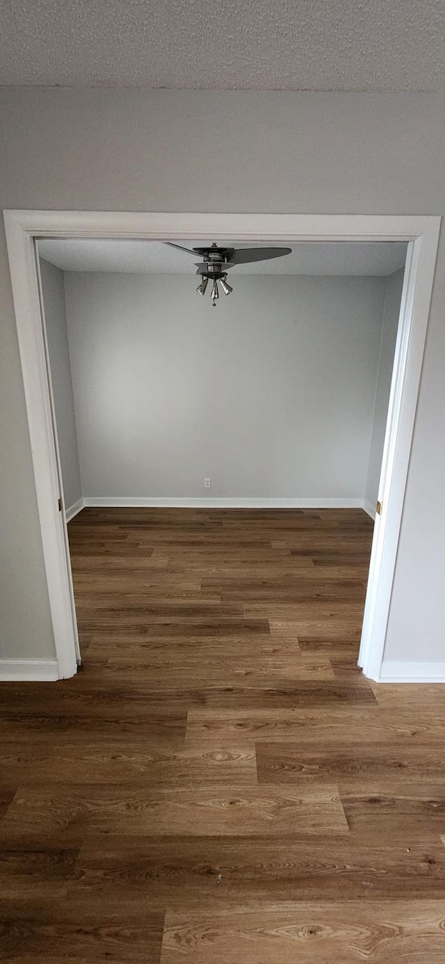 empty room with dark wood-type flooring, ceiling fan, and a textured ceiling