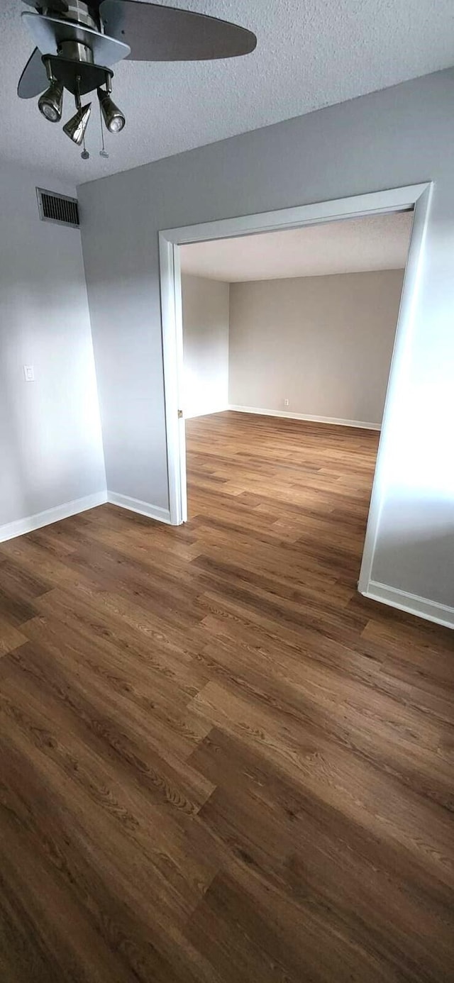 unfurnished room featuring ceiling fan, dark hardwood / wood-style flooring, and a textured ceiling