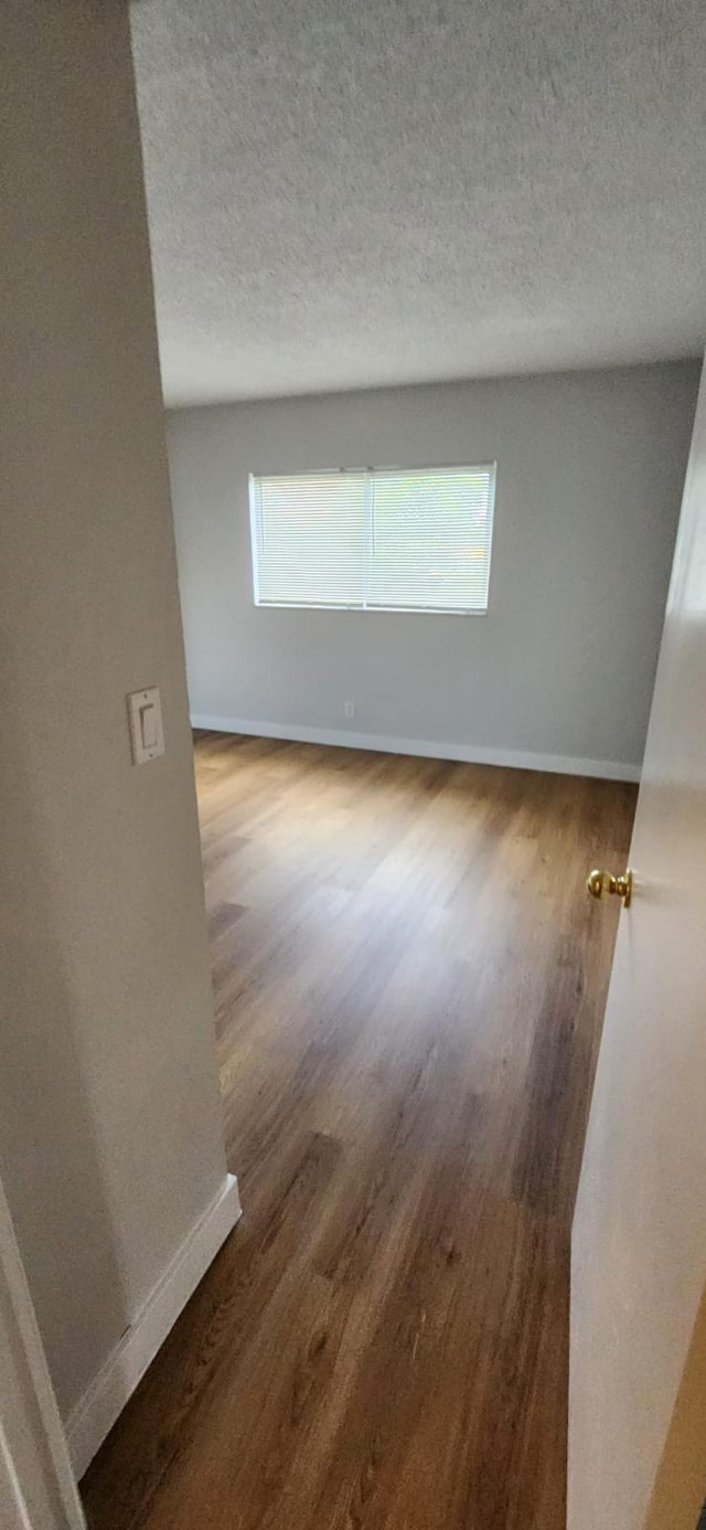 empty room featuring dark hardwood / wood-style flooring and a textured ceiling