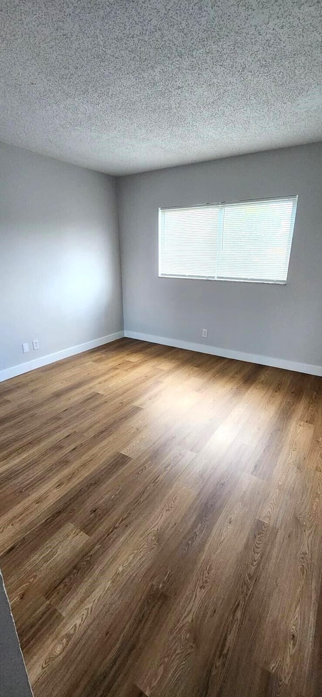 unfurnished room featuring dark wood-type flooring and a textured ceiling