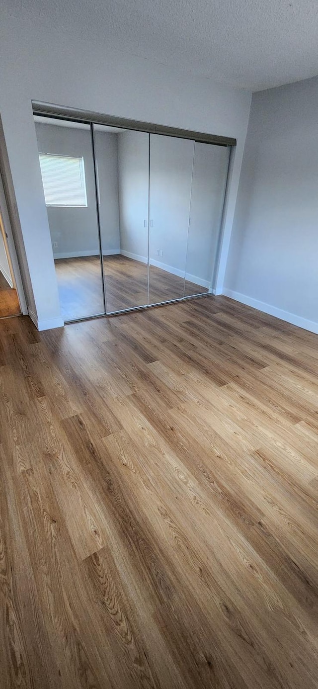 unfurnished bedroom featuring light hardwood / wood-style flooring, a closet, and a textured ceiling