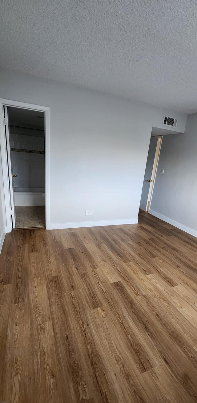 spare room featuring wood-type flooring and a textured ceiling