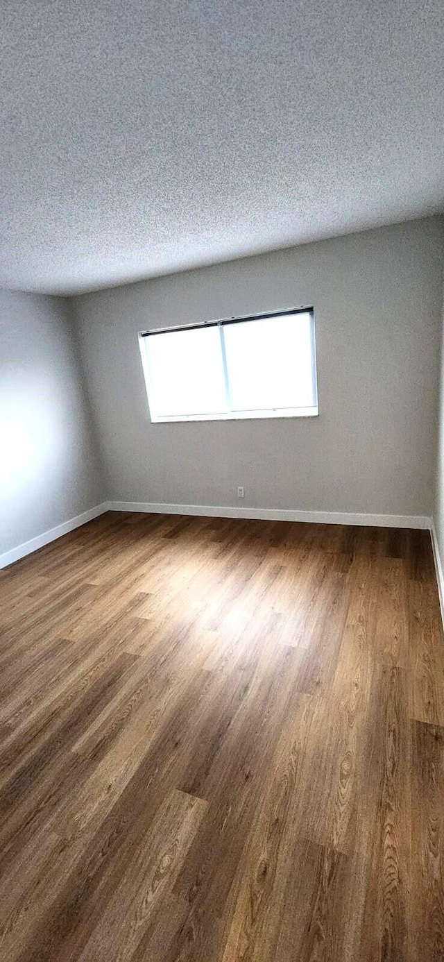 unfurnished room with plenty of natural light, a textured ceiling, and dark hardwood / wood-style flooring