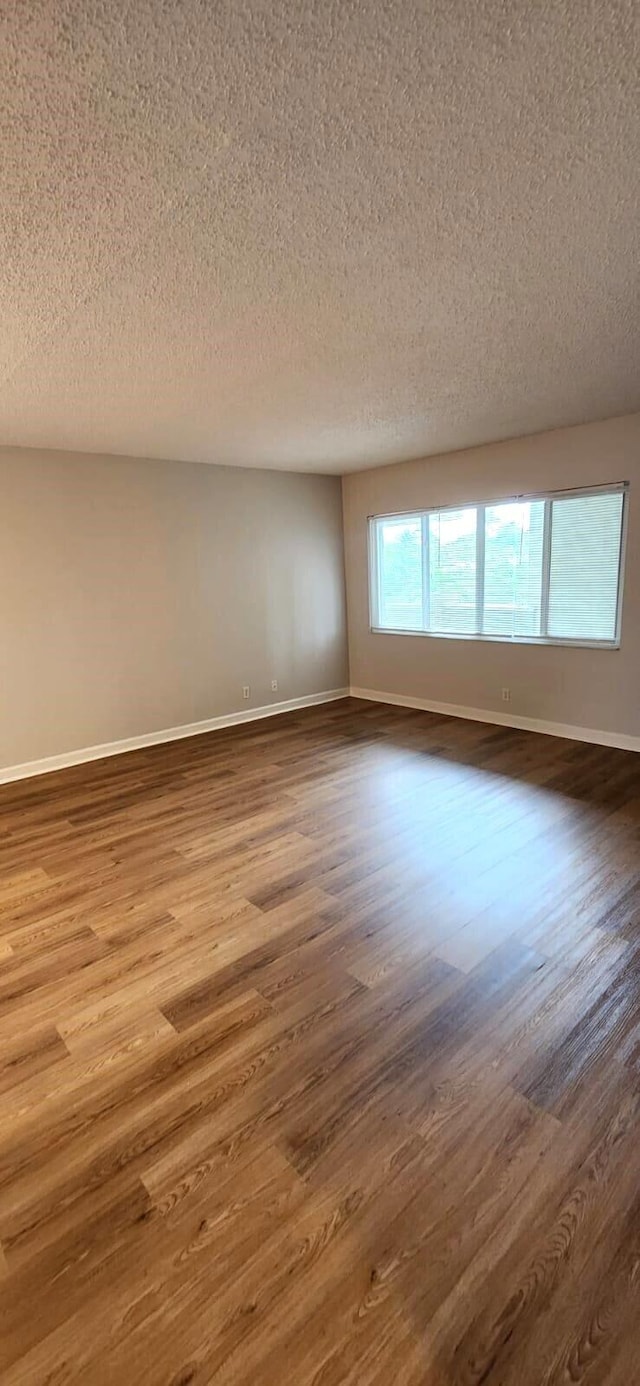 empty room with hardwood / wood-style floors and a textured ceiling