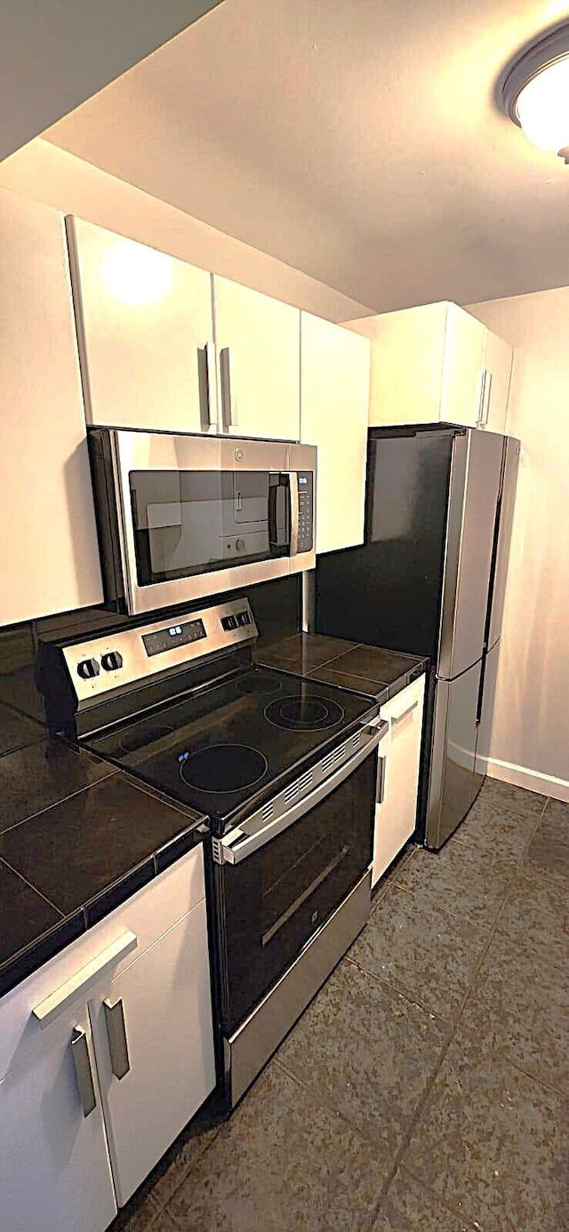 kitchen with tile counters, white cabinets, and appliances with stainless steel finishes