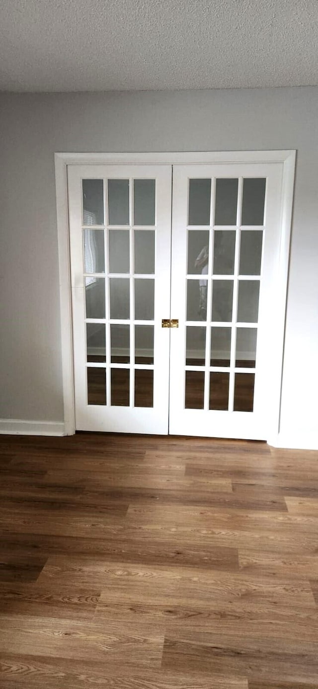 doorway with french doors, wood-type flooring, and a textured ceiling