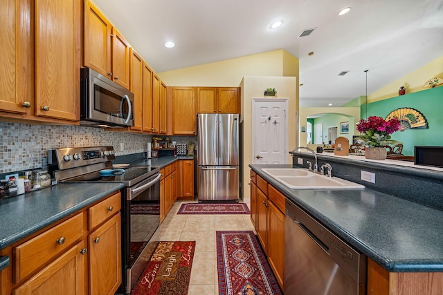 kitchen with light tile patterned flooring, tasteful backsplash, lofted ceiling, sink, and stainless steel appliances