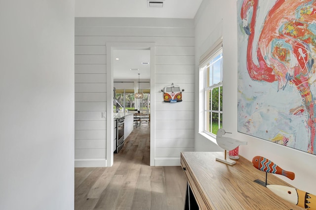 corridor featuring light hardwood / wood-style flooring, a wealth of natural light, and wood walls