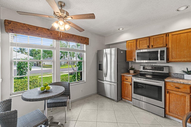 kitchen with ceiling fan, light tile patterned flooring, a textured ceiling, and appliances with stainless steel finishes