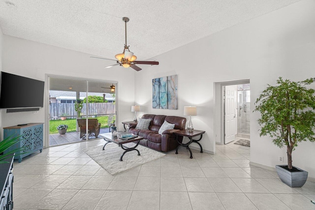 living room featuring ceiling fan, high vaulted ceiling, light tile patterned floors, and a textured ceiling