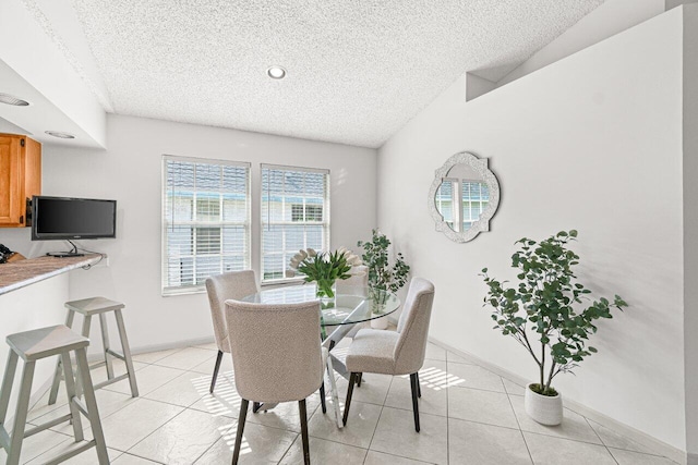 dining space with light tile patterned flooring, vaulted ceiling, and a textured ceiling