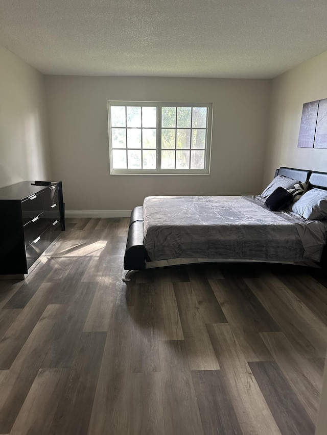 bedroom with dark hardwood / wood-style flooring and a textured ceiling