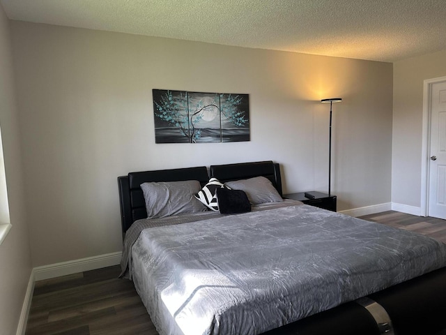 bedroom with dark hardwood / wood-style floors and a textured ceiling