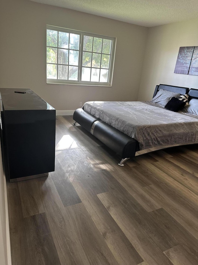 bedroom featuring a textured ceiling and dark hardwood / wood-style flooring