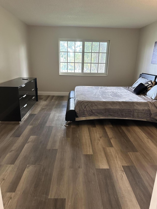 bedroom featuring dark hardwood / wood-style flooring and a textured ceiling