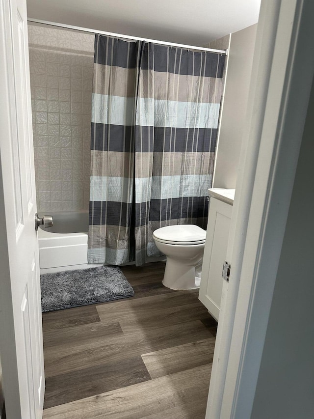 full bathroom with wood-type flooring, toilet, vanity, and shower / tub combo with curtain