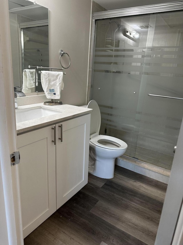 bathroom featuring vanity, an enclosed shower, hardwood / wood-style flooring, and toilet