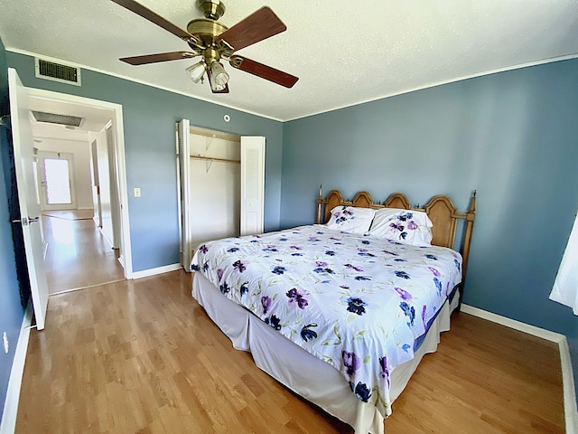 bedroom featuring ceiling fan, a textured ceiling, light wood-type flooring, and a closet