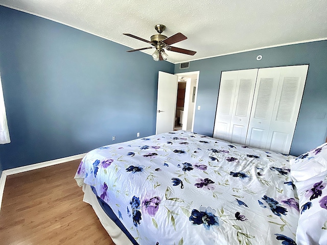 bedroom with ceiling fan, hardwood / wood-style floors, a closet, and a textured ceiling