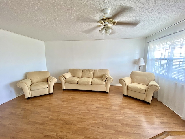 living room featuring ceiling fan, a textured ceiling, and light wood-type flooring