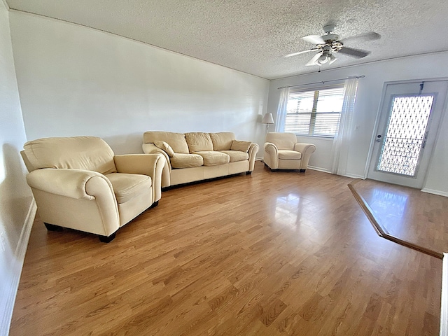 unfurnished living room with ceiling fan, a textured ceiling, and light hardwood / wood-style floors