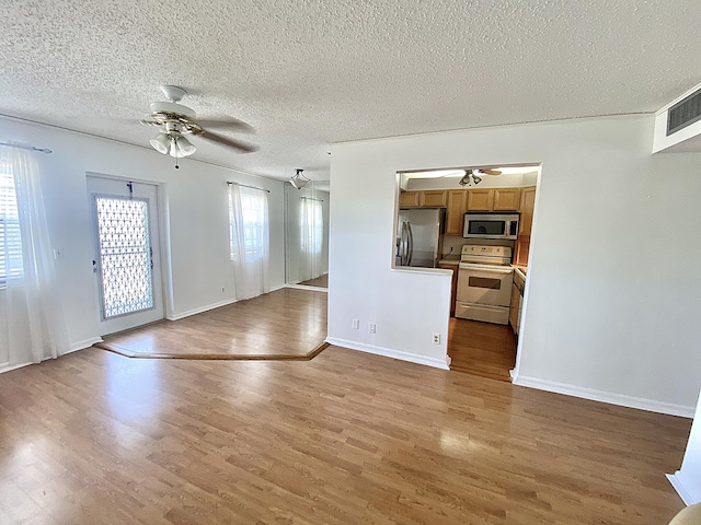 unfurnished living room featuring hardwood / wood-style flooring, a wealth of natural light, and ceiling fan