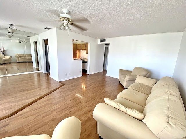 living room with ceiling fan, hardwood / wood-style floors, and a textured ceiling