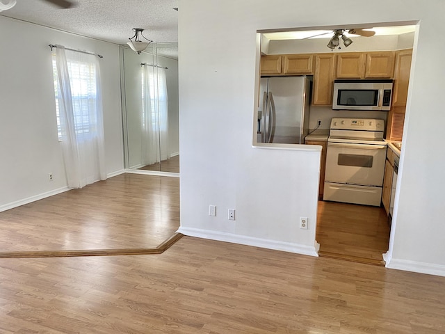 kitchen with ceiling fan, appliances with stainless steel finishes, a textured ceiling, and light hardwood / wood-style floors