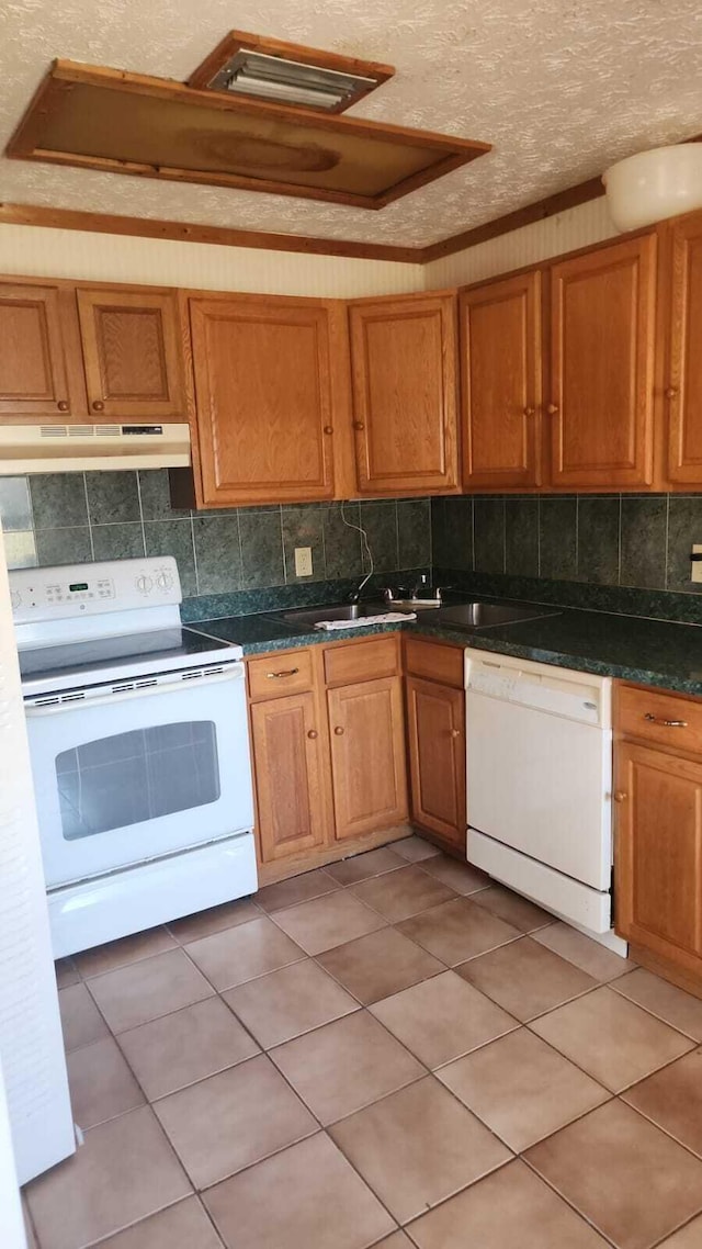 kitchen featuring light tile patterned flooring, backsplash, white appliances, crown molding, and a textured ceiling