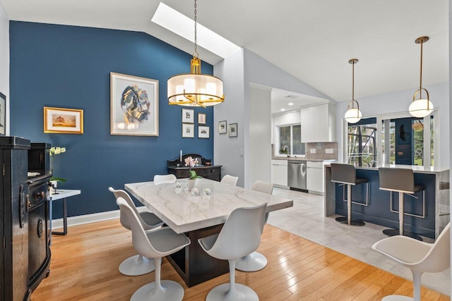 dining area with a notable chandelier, vaulted ceiling, and light wood-type flooring