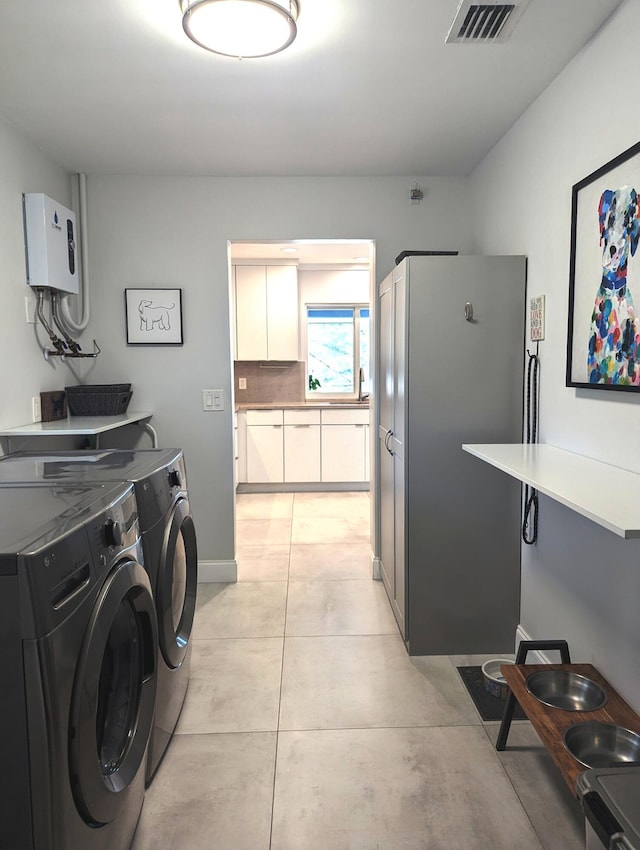 laundry area with water heater and washing machine and clothes dryer