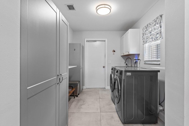 washroom with independent washer and dryer, cabinets, and light tile patterned floors