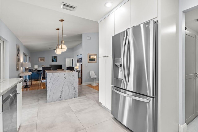 kitchen featuring vaulted ceiling, appliances with stainless steel finishes, pendant lighting, white cabinetry, and light stone counters