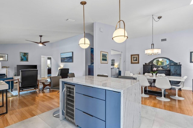 kitchen with pendant lighting, beverage cooler, a kitchen island, and light wood-type flooring