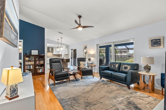 living room with ceiling fan, lofted ceiling, and hardwood / wood-style floors