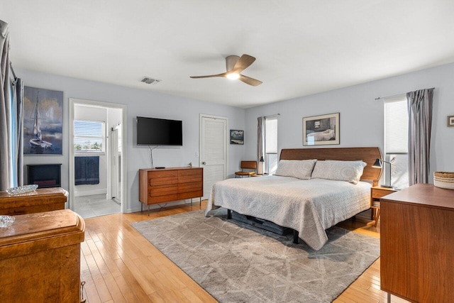 bedroom with ceiling fan, ensuite bathroom, and light hardwood / wood-style floors