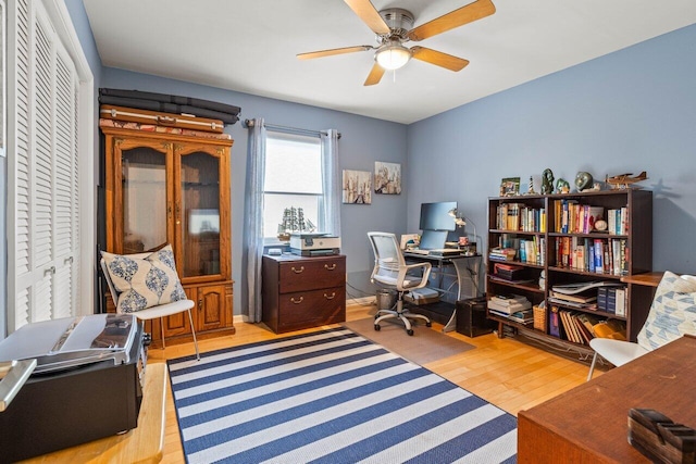 office with light hardwood / wood-style flooring and ceiling fan